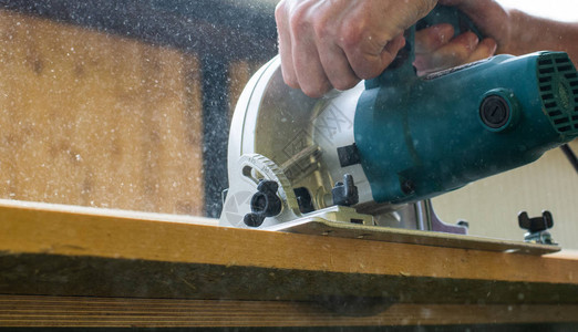 木匠使用圆锯和手动电工具切割木板图片