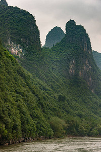 森林中喀斯特山脉链条的肖像几乎垂直地竖立在灰色云层图片