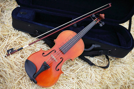 一把小提琴和一把弓放在田里的一堆稻草上音乐小提琴训练提琴手图片