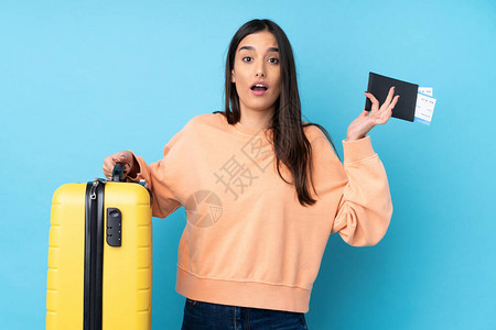 年青黑发女人在放假时带着手提箱护照和惊讶的蓝色图片