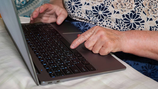 老年妇女正在笔记本电脑上打字图片