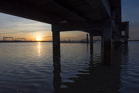 夕阳下平静的海水中反射着木制码头的海岸景观图片