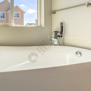 光线照耀的浴室内有格罗斯浴缸和挂在墙上的毛巾棒图片