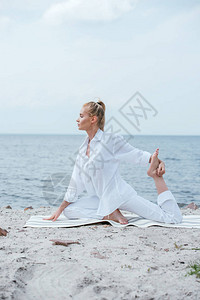 金发年轻女子在河边练习瑜伽的侧视图图片