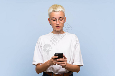 蓝墙上短发白的少女用手机传递信息并用图片