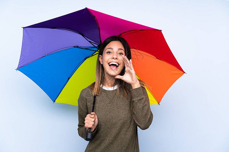 年轻的黑发女人拿着雨伞在隔绝的蓝墙上张图片