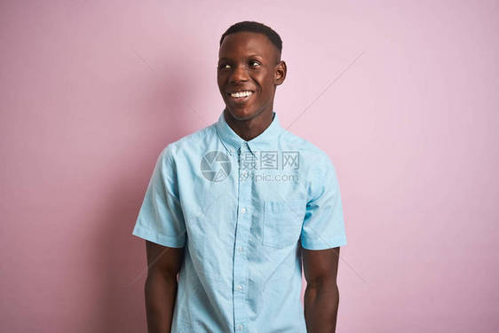 身穿蓝色轻便衬衫的非洲美国人站在孤立的粉红色背景上图片