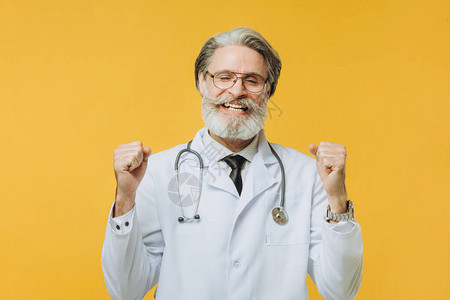 身着听诊器的高级灰头发医生男子站在孤立的黄色背景之上图片