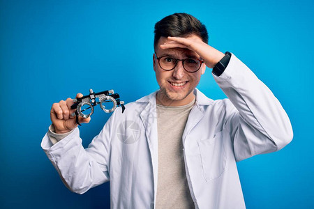 年轻英俊的专业眼科医生在蓝色背景上戴着几何眼镜图片