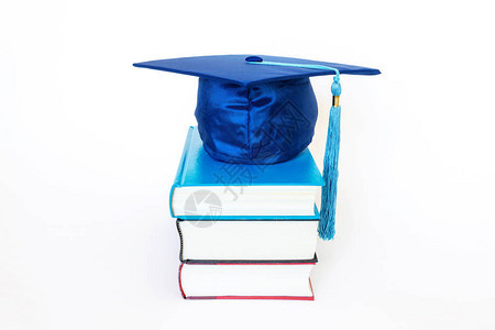 在白色背景上孤立的书籍顶部的蓝色毕业图片