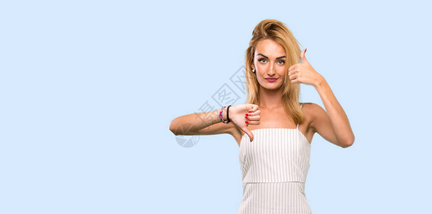 年轻的金发女人做出好坏的迹象在孤立的蓝色背景上是与否图片