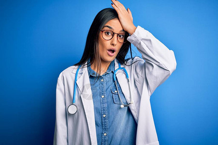 年轻漂亮的女医生戴着听诊器和蓝色背景的眼镜图片