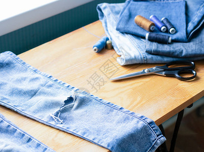手工艺品服装修理蓝牛仔裤脱落的蓝色牛仔裤放在木制桌子上经济再利用事物的概念横向图片
