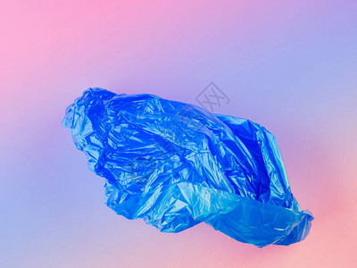 粉红色背景上皱巴的蓝色塑料垃圾袋图片