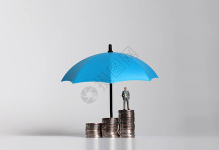微型商人拿着伞站在一堆硬币上图片