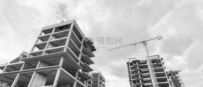蓝天背景下在建多层住宅楼和起重机的黑白全景图片
