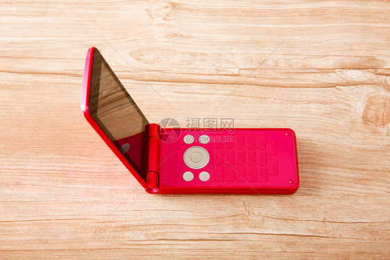 红色手机在木制桌子上将侧道图片