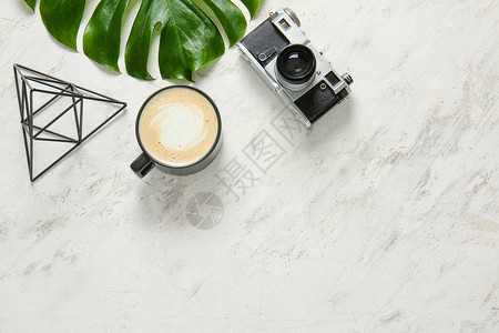 浅色背景下的咖啡照相机和热带树叶图片