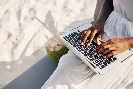 妇女坐在沙滩上并从事笔记本电脑编码或答复电子邮件的妇图片