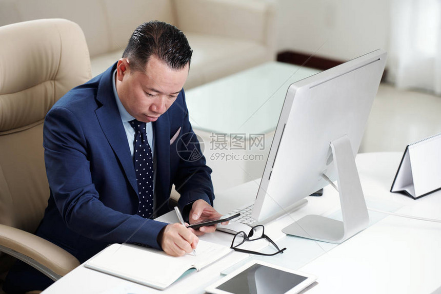 严肃的亚洲办公室工作人员坐在办公桌前高清图片下载-正版图片504461217-摄图网