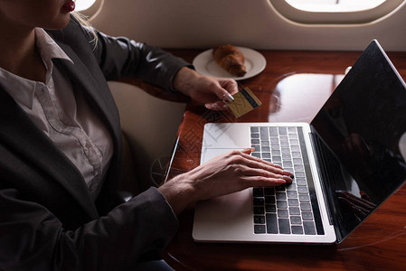 商业旅行期间在飞机上工作信用卡和笔记本电脑的商业图片