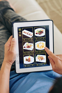 手持平板电脑的人选择餐盘从餐厅申请图片