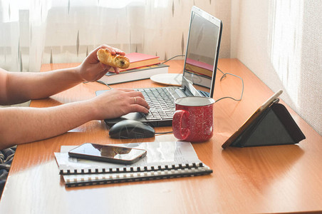 裁剪的人在家工作使用和吃甜圈远程工作或在线教育或待图片