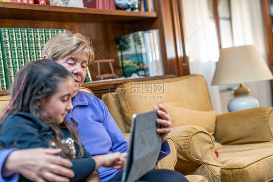 年轻女孩在家里与祖母一起学习科罗纳病图片
