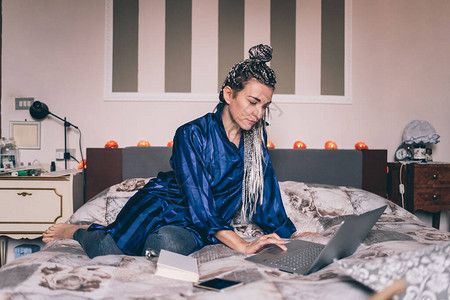 成年人妇女用计算机穿夜装睡床上智能工作屏幕时图片