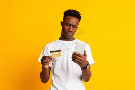 年轻非洲人无法理解如何用黄背景的信用卡在网上支付费用图片