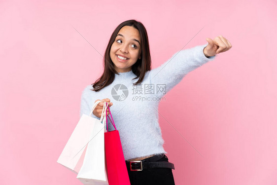 年轻女人拿着购物袋在孤立的粉红背景上买包图片