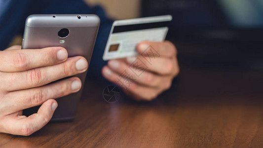 人手使用智能手机并持有信用卡进行网上购物和支付图片