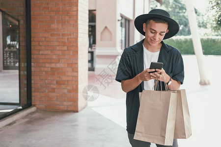拥有纸袋和手机智能电话的男子使用纸袋购物袋图片