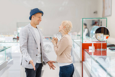 年轻的爱夫妇在珠宝店买珠宝男人和女人选择结婚戒指未来的新娘和图片