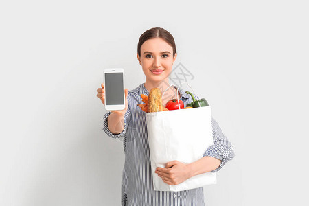 食品装袋和轻型移动电话的青年妇女图片