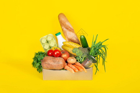 送餐购物或捐赠概念验尸官检疫期间的食品运送黄色背景中分离的水果蔬菜牛奶鸡蛋等不同食图片
