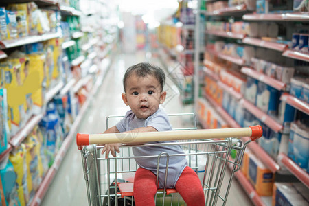独自坐在购物车或杂货超市推车的婴图片