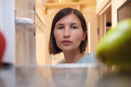 漂亮的亚洲女人在冰箱里寻找食物健康食品的概念在隔离期间暴饮食和延图片