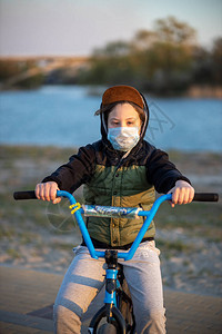 一个少年在日落时戴着面具骑着蓝色自行车的画像隔离禁止骑自行图片