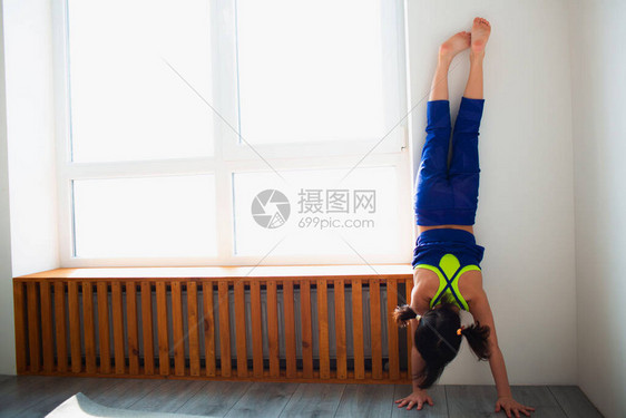 小女孩在家锻炼倒立俯卧撑可爱的孩子站在室内木制窗台附近的手上穿着运动服的黑发小女在她房间的窗图片