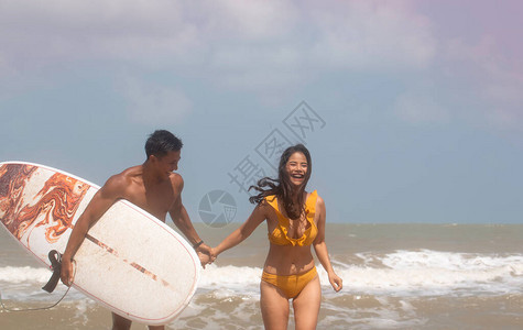年轻的女士和英俊的男子拿着右手的冲浪板用快乐的感觉说话模特装扮满脸大图片