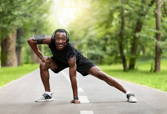 运动的黑人在城市公园训练前伸展身体听音乐享受上午锻炼空闲图片