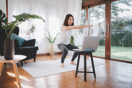 快乐的亚洲妇女在家里从笔记本电脑上学习在线健身解剖课程图片