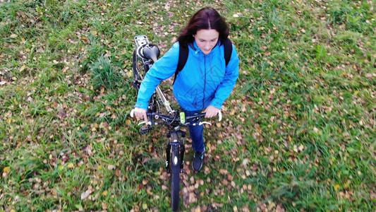 妇女骑自行车在秋天公园行走图片