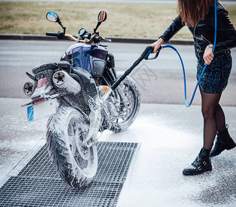 一位女骑自行车的人在服务中清洗她的休闲自行车在城市洗车街头摩托车图片