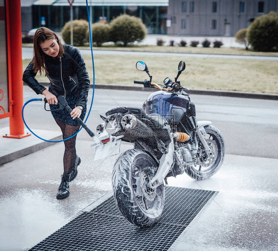 漂亮可爱的女孩照顾她的车市内的洗车服务城市运动摩托车图片