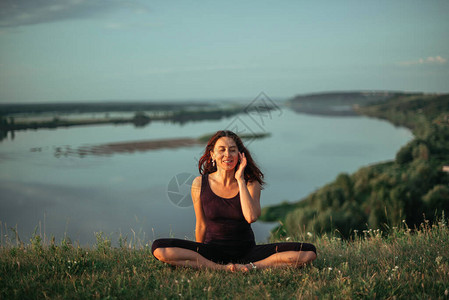 日出时的瑜伽练习和冥想质妇女在大河图片