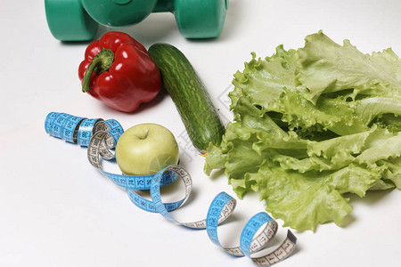 在白色背景饮食和运动上隔离的蔬菜和计量带图片