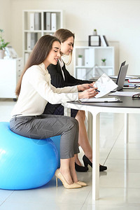 女青年在办公室工作时坐在健身球图片