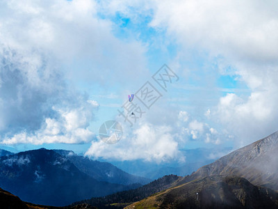滑翔伞上的一个人飞过山地上天空中的云烟雾图片
